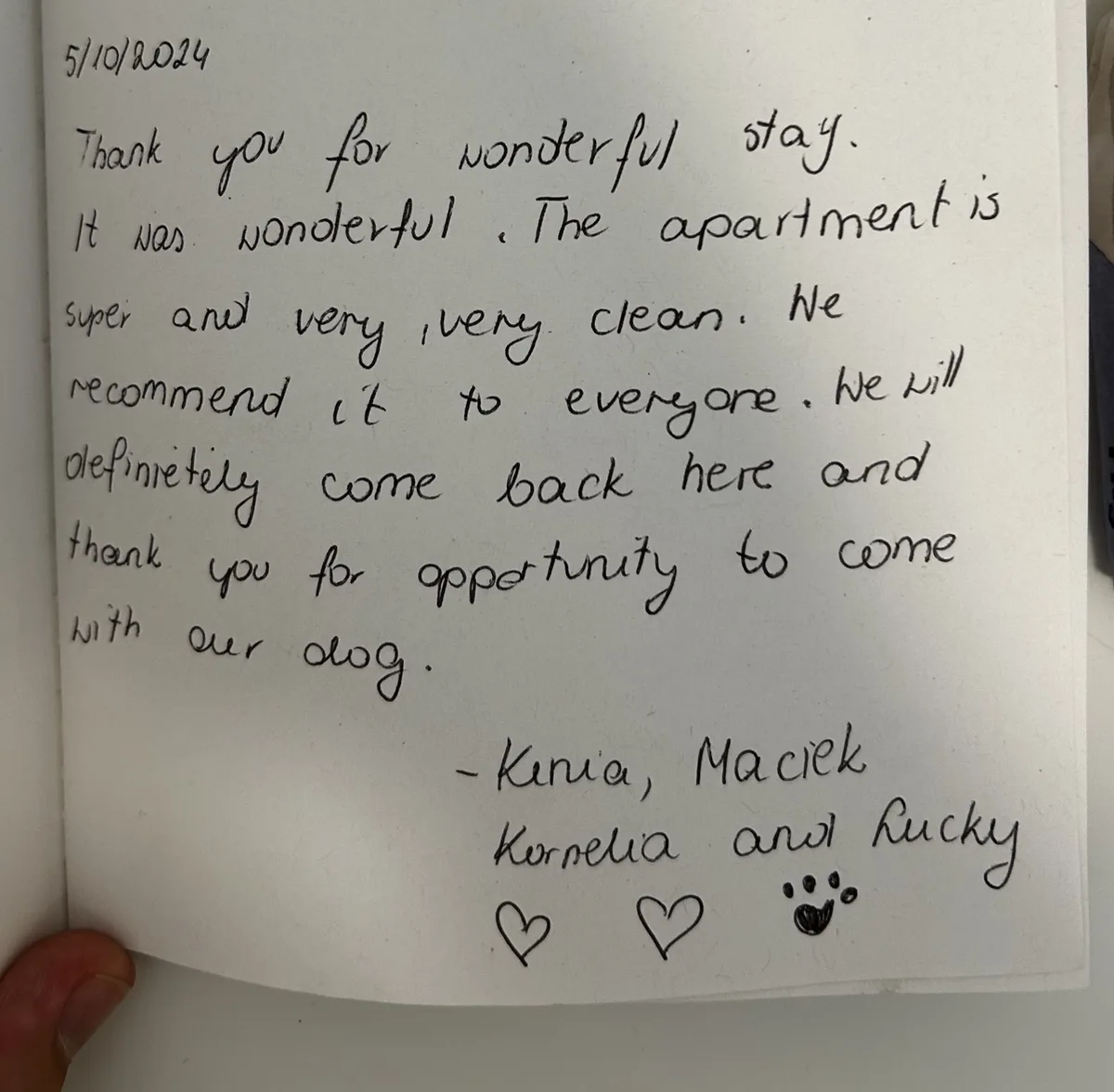 Handwritten guestbook note thanking the hosts for a wonderful, very clean stay and for welcoming the family dog, signed with two hearts and a paw print.